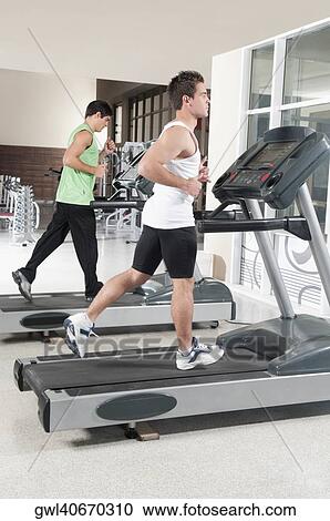 Stock Image - Two men running on treadmills. Fotosearch