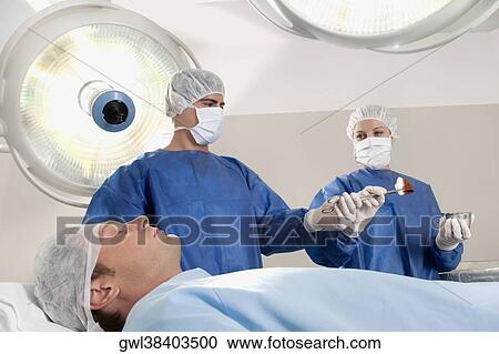 Two surgeons operating a patient in an operating room View Large Photo Image Stock Image - Two surgeons operating a patient in an operating room. Fotosearch