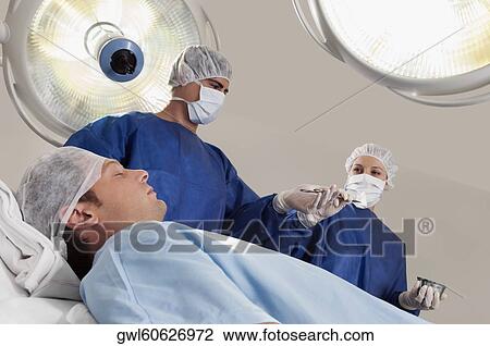 Two surgeons operating a patient in an operating room View Large Photo Image Stock Image - Two surgeons operating a patient in an operating room. Fotosearch