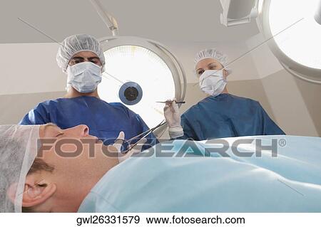 Two surgeons operating a patient in an operating room View Large Photo Image Stock Photo - Two surgeons operating a patient in an operating room. Fotosearch