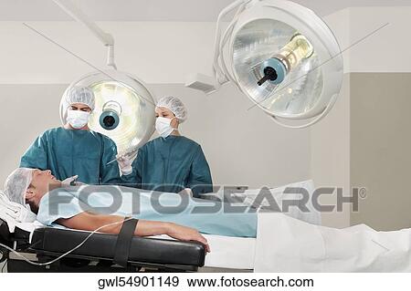 Two surgeons operating a patient in an operating room View Large Photo Image Stock Photo - Two surgeons operating a patient in an operating room. Fotosearch