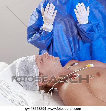 Picture - Two surgeons with a patient in an operating room. Fotosearch