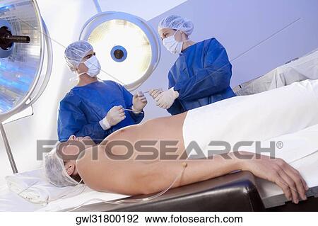 Two surgeons with a patient in an operating room View Large Photo Image Stock Image - Two surgeons with a patient in an operating room. Fotosearch