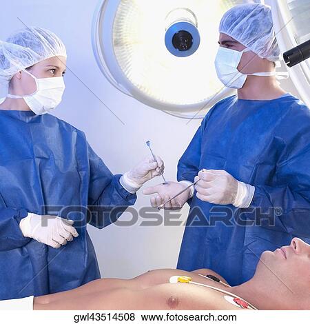 Two surgeons with a patient in an operating room View Large Photo Image Stock Photo - Two surgeons with a patient in an operating room. Fotosearch