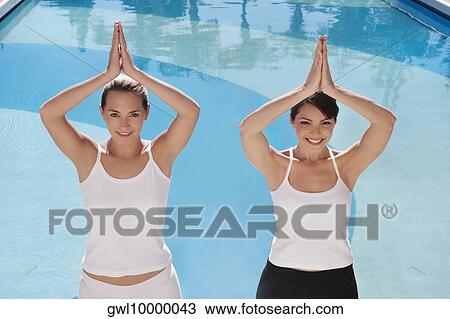 Stock Image - Two women in prayer position at the poolside. Fotosearch