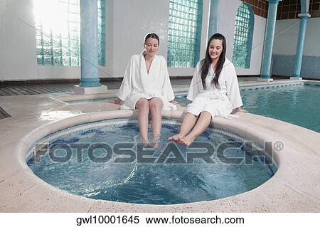 Two women sitting at the poolside with their feet soaking in water View Large Photo Image Stock Photography - Two women sitting at the poolside with their feet soaking in water. Fotosearch