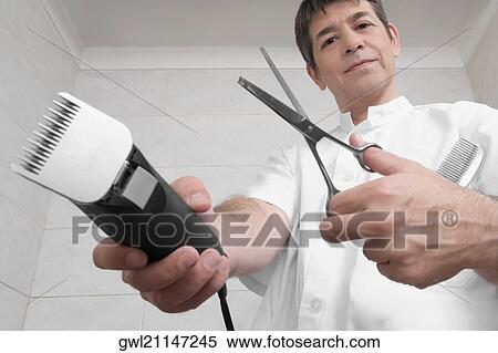 Stock Photography - Vet holding an electric razor and scissors. Fotosearch