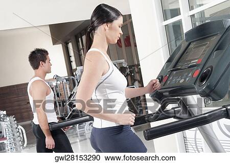 Woman and a man walking on treadmills View Large Photo Image Stock Image - Woman and a man walking on treadmills. Fotosearch