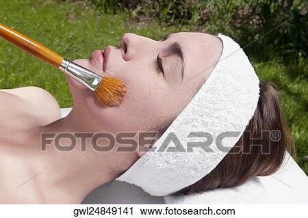 Stock Image - Woman applying a facial mask. Fotosearch
