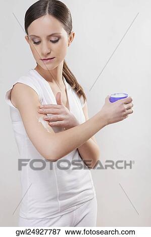 Stock Photo - Woman applying moisturizer cream on her arm. Fotosearch