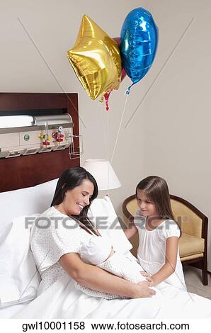 Woman carrying her newborn baby with her daughter in a hospital View Large Photo Image Stock Photo - Woman carrying her newborn baby with her daughter in a hospital. Fotosearch