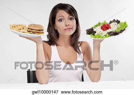 Woman choosing between a hamburger and salad View Large Photo Image Stock Photo - Woman choosing between a hamburger and salad . Fotosearch