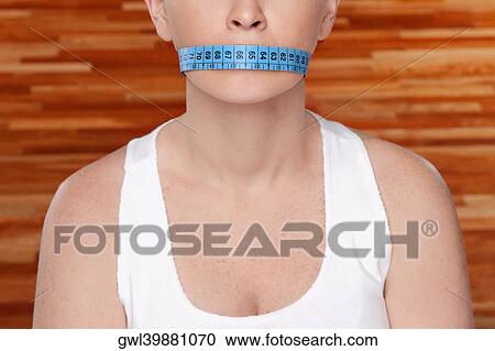 Woman covering her mouth with a tape measure View Large Photo Image Stock Image - Woman covering her mouth with a tape measure. Fotosearch