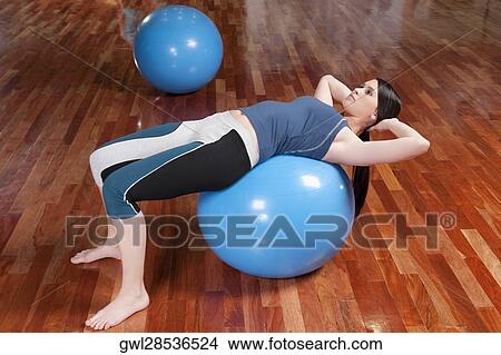 Woman doing sit-ups on a fitness ball View Large Photo Image Picture - Woman doing sit-ups on a fitness ball. Fotosearch