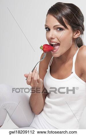 Woman eating a strawberry on a fork View Large Photo Image Stock Image - Woman eating a strawberry on a fork. Fotosearch