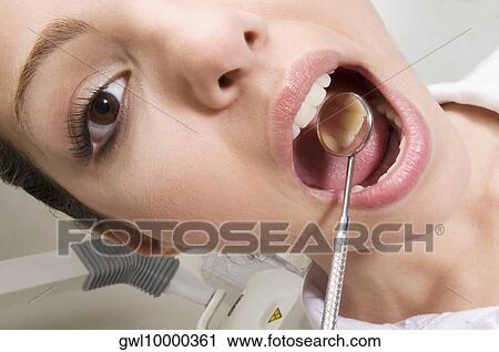 Woman examining her teeth with angled mirror View Large Photo Image Stock Image - Woman examining her teeth with angled mirror. Fotosearch