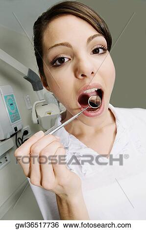 Woman examining her teeth with angled mirror View Large Photo Image Stock Photograph - Woman examining her teeth with angled mirror. Fotosearch