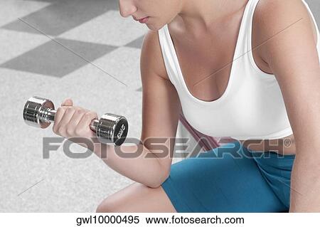 Woman exercising with a dumbbell View Large Photo Image Stock Photography - Woman exercising with a dumbbell. Fotosearch