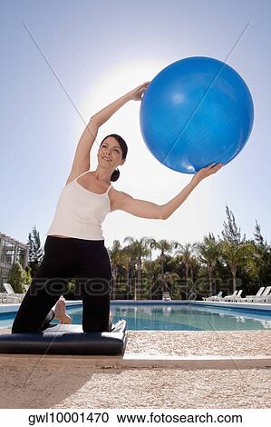 Woman exercising with a fitness ball at the poolside View Large Photo Image Stock Image - Woman exercising with a fitness ball at the poolside. Fotosearch