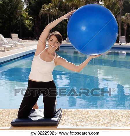 Woman exercising with a fitness ball at the poolside View Large Photo Image Stock Photography - Woman exercising with a fitness ball at the poolside. Fotosearch