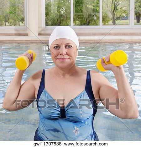 Woman exercising with dumbbells in a swimming pool View Large Photo Image Stock Photo - Woman exercising with dumbbells in a swimming pool. Fotosearch