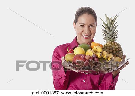 Woman holding a basket of fruits View Large Photo Image Stock Photo - Woman holding a basket of fruits. Fotosearch