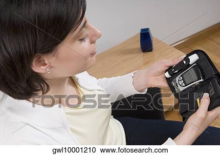 Stock Image - Woman holding a blood sugar testing kit. Fotosearch