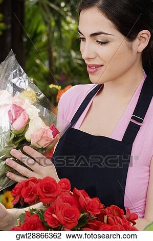 Stock Image - Woman holding a bouquet of flowers in a greenhouse. Fotosearch