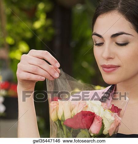 Woman holding a bouquet of flowers in a greenhouse View Large Photo Image Stock Photograph - Woman holding a bouquet of flowers in a greenhouse. Fotosearch