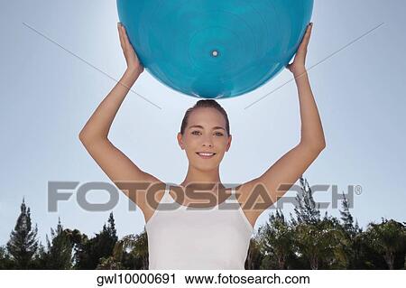 Woman holding a fitness ball and smiling View Large Photo Image Stock Image - Woman holding a fitness ball and smiling. Fotosearch