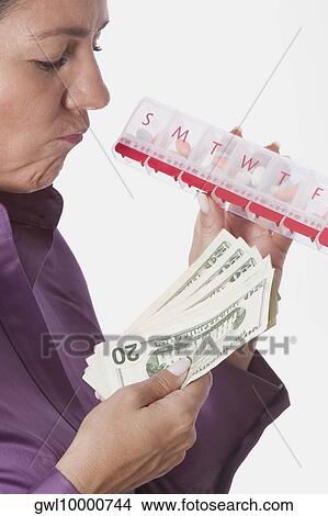 Woman holding a pill box and currency notes View Large Photo Image Picture - Woman holding a pill box and currency notes. Fotosearch
