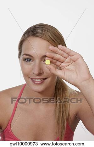 Woman holding a pill in front of her eye View Large Photo Image Stock Image - Woman holding a pill in front of her eye. Fotosearch
