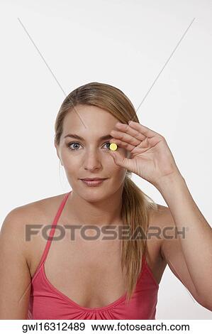 Woman holding a pill in front of her eye View Large Photo Image Stock Photo - Woman holding a pill in front of her eye. Fotosearch