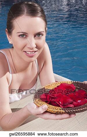 Woman holding a plate of rose petals at the poolside View Large Photo Image Picture - Woman holding a plate of rose petals at the poolside. Fotosearch