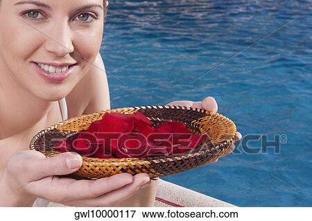 Woman holding a plate of rose petals at the poolside View Large Photo Image Stock Photo - Woman holding a plate of rose petals at the poolside. Fotosearch
