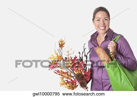 Woman holding a shopping bag of groceries and a bunch of maple leaves View Large Photo Image Stock Photography - Woman holding a shopping bag of groceries and a bunch of maple leaves. Fotosearch