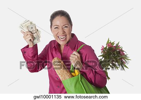 Woman holding a shopping bag of groceries and showing currency notes View Large Photo Image Stock Photography - Woman holding a shopping bag of groceries and showing currency notes. Fotosearch