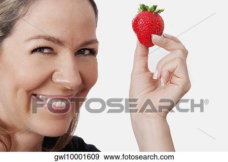 Stock Photo - Woman holding a strawberry. Fotosearch