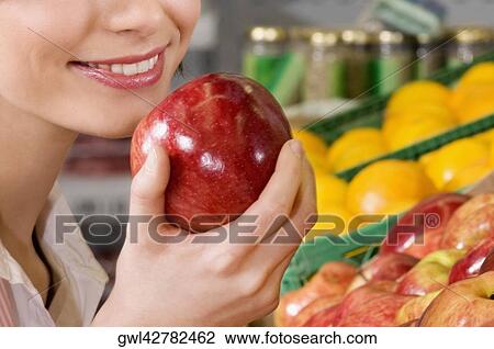Woman holding an apple in a supermarket View Large Photo Image Stock Image - Woman holding an apple in a supermarket. Fotosearch