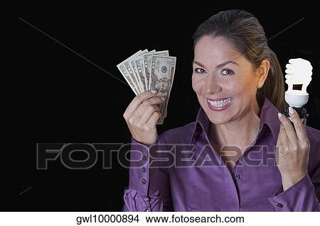 Woman holding currency notes and a compact fluorescent light bulb View Large Photo Image Picture - Woman holding currency notes and a compact fluorescent light bulb. Fotosearch