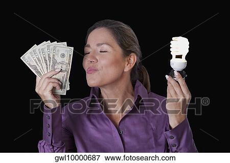 Woman holding currency notes and a compact fluorescent light bulb View Large Photo Image Stock Photo - Woman holding currency notes and a compact fluorescent light bulb. Fotosearch