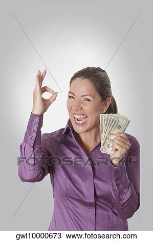 Woman holding currency notes and showing OK sign View Large Photo Image Stock Image - Woman holding currency notes and showing OK sign. Fotosearch