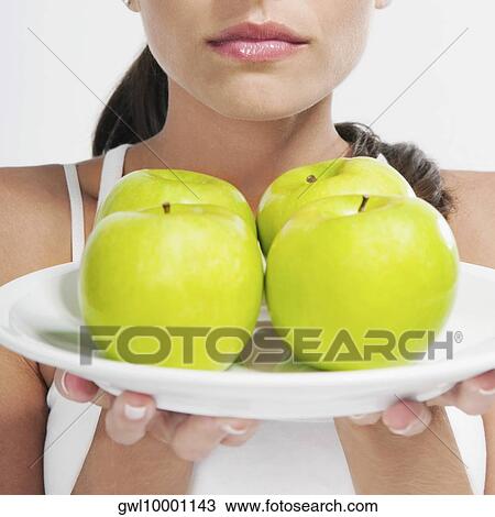 Woman holding green apples on a plate View Large Photo Image Stock Image - Woman holding green apples on a plate. Fotosearch