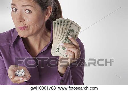 Woman holding pills and currency notes View Large Photo Image Stock Photo - Woman holding pills and currency notes. Fotosearch