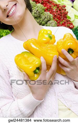 Woman holding yellow bell peppers in a supermarket View Large Photo Image Picture - Woman holding yellow bell peppers in a supermarket. Fotosearch