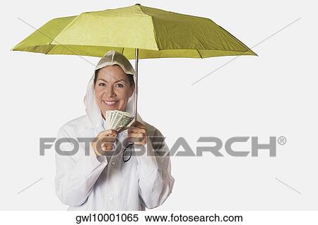 Woman in rain coat sheltering under an umbrella and holding currency notes View Large Photo Image Stock Photography - Woman in rain coat sheltering under an umbrella and holding currency notes. Fotosearch