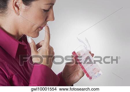 Woman looking at a pill box View Large Photo Image Picture - Woman looking at a pill box. Fotosearch