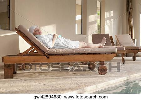 Stock Image - Woman lying on a lounge chair in a rehabilitation center. Fotosearch