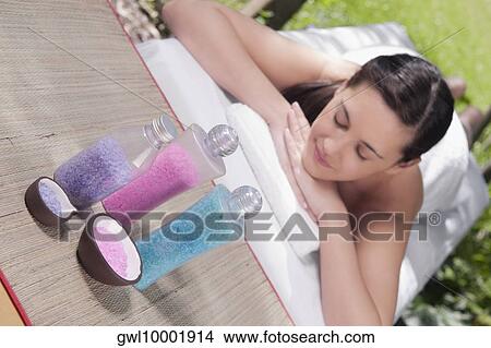 Woman lying on a massage table with bath salt View Large Photo Image Picture - Woman lying on a massage table with bath salt. Fotosearch