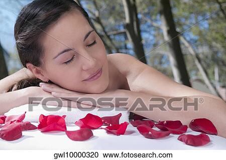 Woman lying on a massage table with rose petals in front of her View Large Photo Image Stock Image - Woman lying on a massage table with rose petals in front of her. Fotosearch